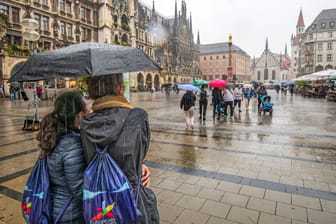 Menschen stehen mit Regenschirm auf dem Marienplatz (Symbolbild): Am Wochenende könnte es in Bayern ungemütlich werden – auch in München.