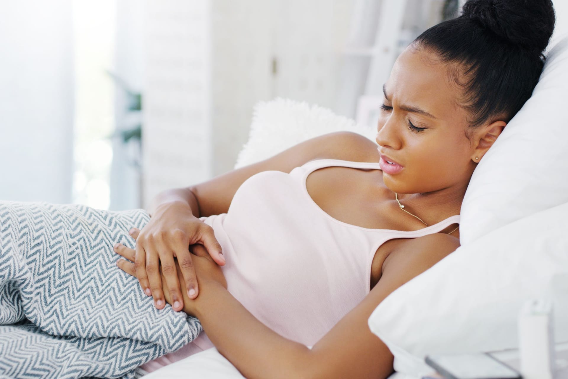 Frau mit Bauchschmerzen im Bett Frau mit Bauchschmerzen im Bett