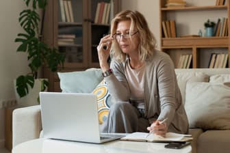 Eine Frau blickt auf ihr Laptop (Symbolbild): Viele Menschen möchten früher in Rente gehen, als es die gesetzliche Regelaltersgrenze vorsieht.