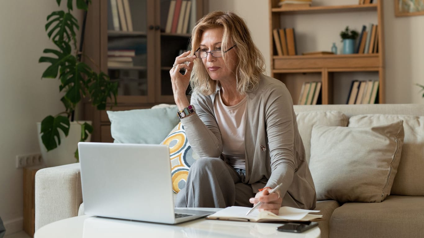 Eine Frau blickt auf ihr Laptop (Symbolbild): Viele Menschen möchten früher in Rente gehen, als es die gesetzliche Regelaltersgrenze vorsieht.