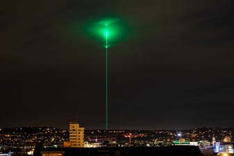 Ein grüner Laser strahlt am nächtlichen Himmel über Stuttgart: Ein Laser der Firma Trumpf soll zum 100. Firmenjubiläum als besondere "Geburtstagskerze" am Himmel leuchten.