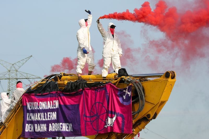 Aktivsten der Gruppe "Ende Gelände" stehen mit Transparenten auf dem Bagger einer Baustelle: Hier sollen Rohre für eine LNG-Pipeline verlegt werden.