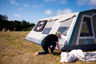 Ein Punk baut in Tinnum ein Zelt auf (Archivbild): Unter dem Motto "Sylt für alle" kritisiert die Gruppe "Aktion Sylt" eine Spaltung der Gesellschaft und hat ein Protestcamp gestartet.