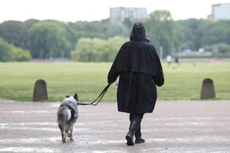 Eine Frau geht bei Regen mit ihrem Hund spazieren (Symbolbild): Der Wochenstart in NRW wird trüb.