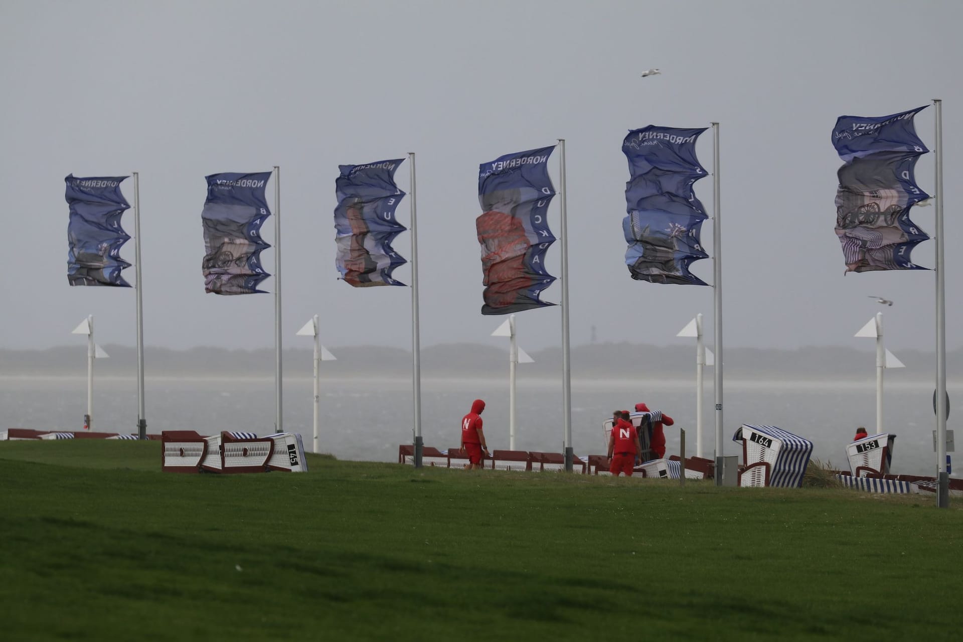 Bei starkem Nordwestwind wehen Fahnen an der Kaiserwiese auf der ostfriesischen Insel Norderney: Sommerurlauber und Küstenbewohner müssen sich auf ein für die Jahreszeit ungewöhnliches Sturmtief einstellen.