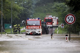 Feuerwehrleute vor einer überfluteten Brücke in der Steiermark: Am Sonntag wurde das erste Todesopfer in Österreich gemeldet.