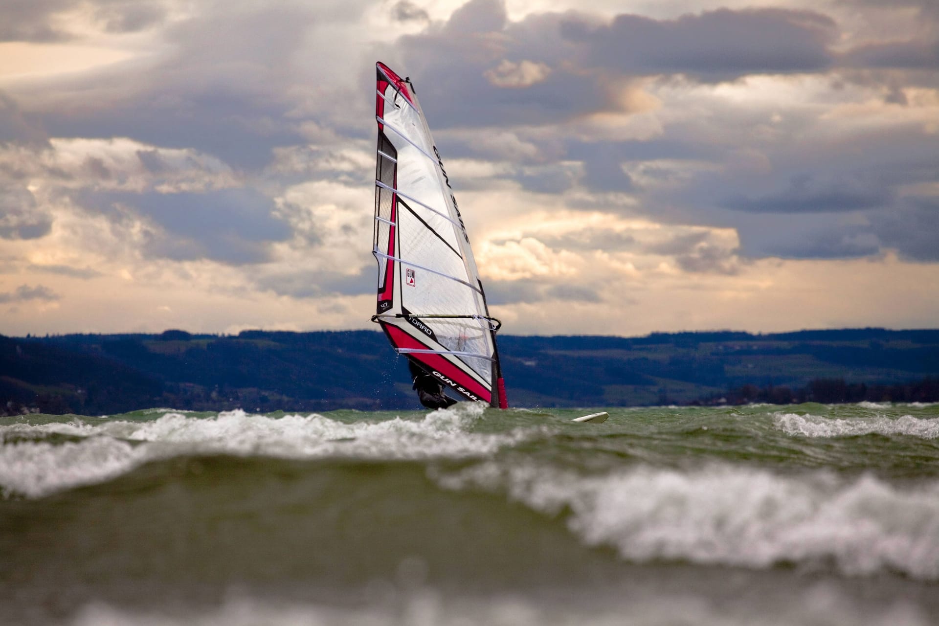 Ein Surfer bei starkem Wind auf dem Bodensee vor der Insel Reichenau (Symbolbild): Rund eine Stunde trieb ein Mann im Wasser, ehe die Rettung kam.