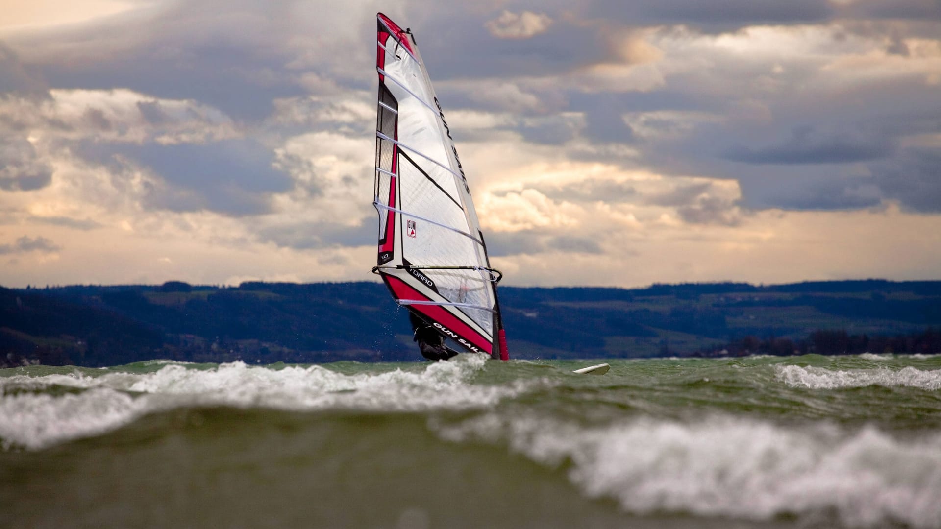 Ein Surfer bei starkem Wind auf dem Bodensee vor der Insel Reichenau (Symbolbild): Rund eine Stunde trieb ein Mann im Wasser, ehe die Rettung kam.