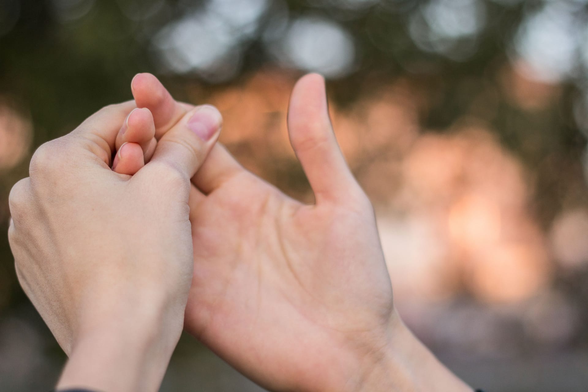 Eine Frau umfasst ihre rechte mit der linken Hand: Bei verdickten Stellen an den Fingerendgelenken kann es sich um Heberden-Knoten handeln. Manche Betroffene hoffen, dass diese von allein wieder weggehen.