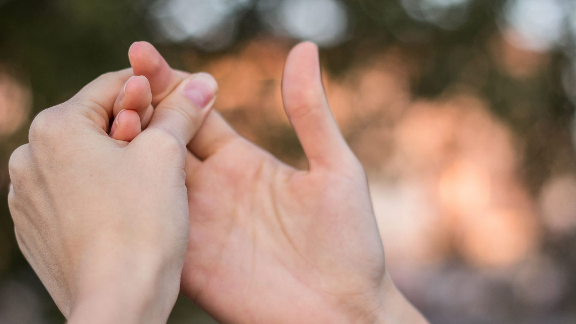 Eine Frau umfasst ihre rechte mit der linken Hand: Bei verdickten Stellen an den Fingerendgelenken kann es sich um Heberden-Knoten handeln. Manche Betroffene hoffen, dass diese von allein wieder weggehen.