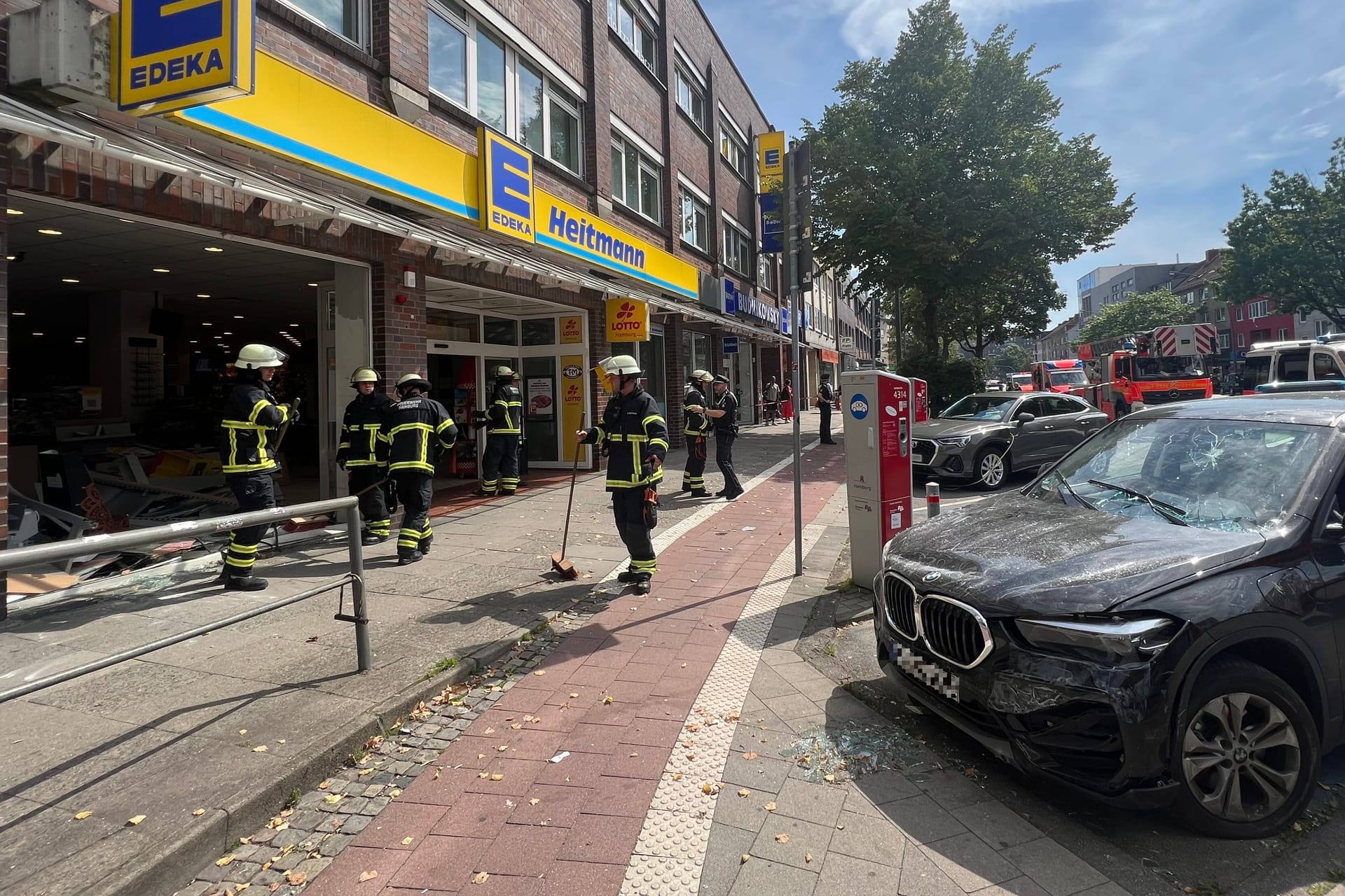 Der Unfallwagen steht vor dem Supermarkt: Die Frontscheibe des Geschäfts ist komplett demoliert.