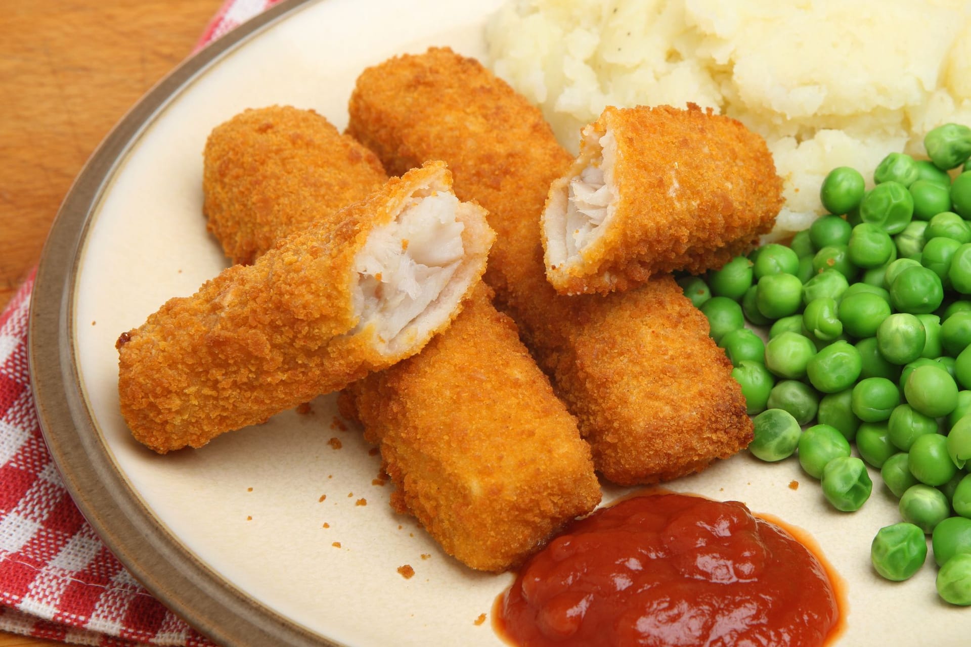 Fischstäbchen passen hervorragend zu Kartoffelbrei und Erbsen.