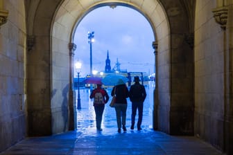 Touristen passieren bei Regen das Georgentor in der Altstadt von Dresden.