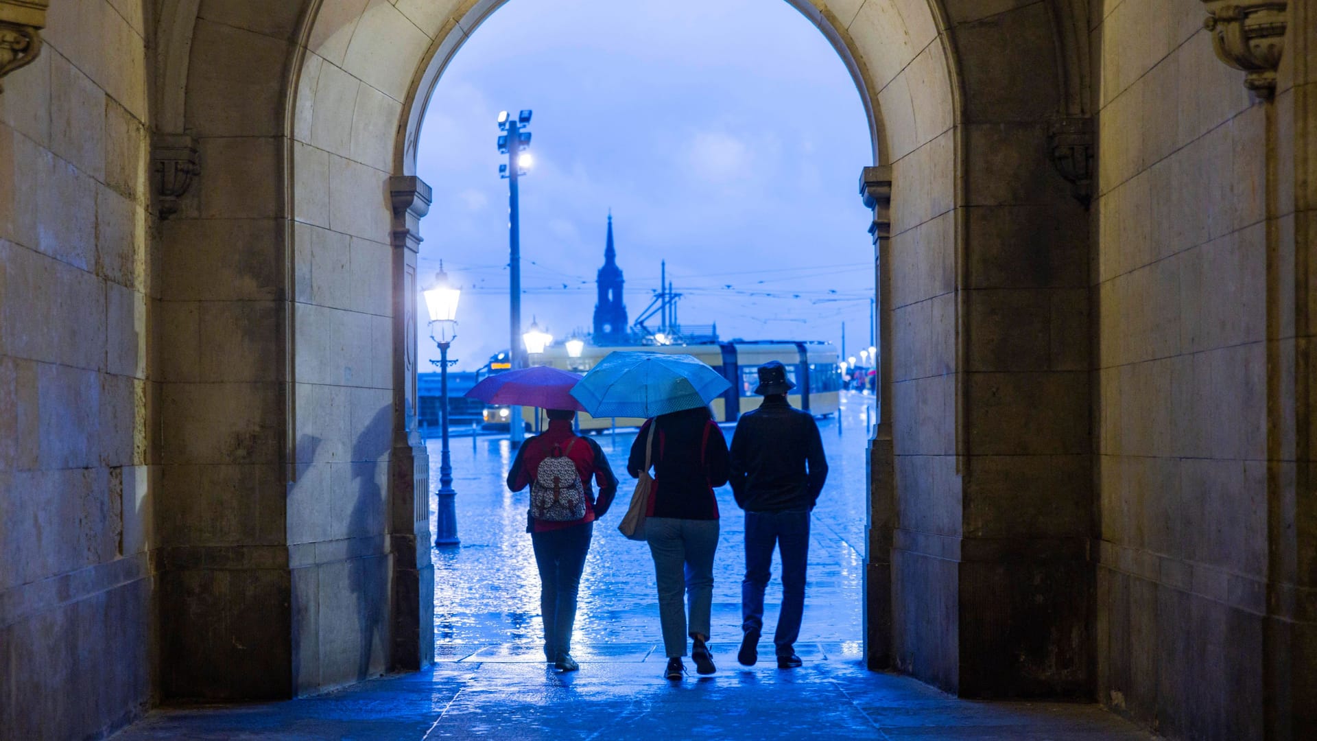 Touristen passieren bei Regen das Georgentor in der Altstadt von Dresden.