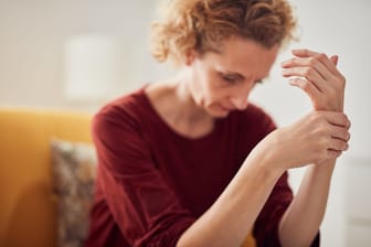Frau mit Fingerschmerzen: Eine Heberden-Arthrose kann mit Schmerzen in den Fingern einhergehen.