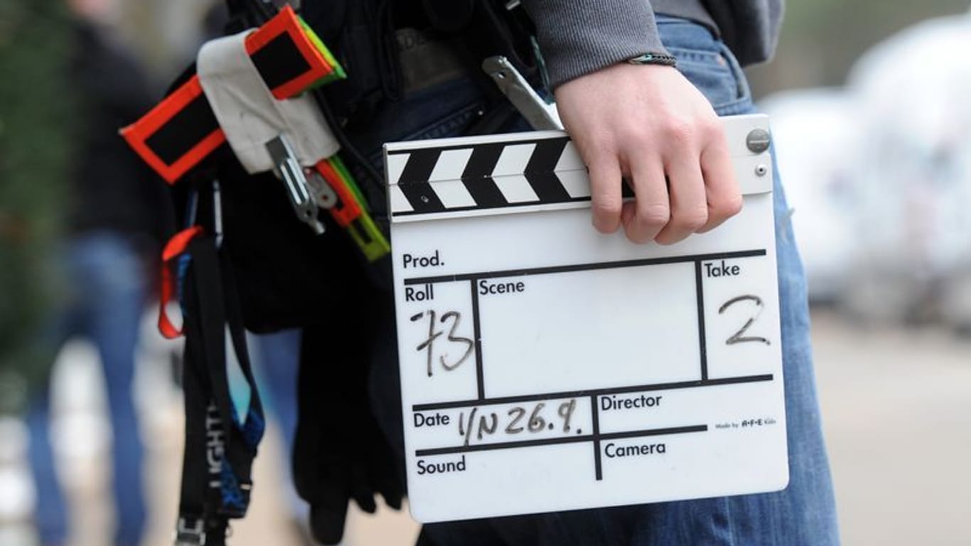 Ein Mitarbeiter eines Filmteams hält eine Filmklappe (Symbolbild): In Köln werden Statisten für einen Kinofilm gesucht.