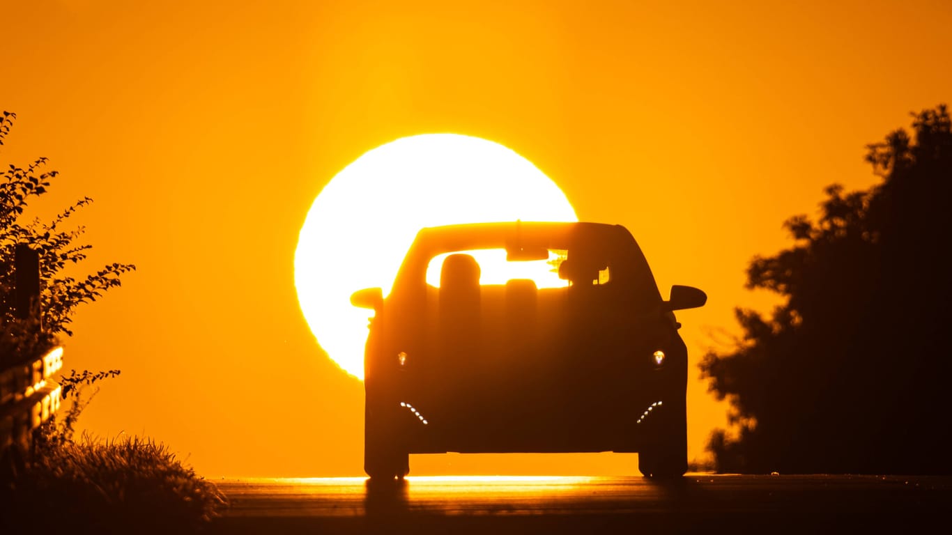 Auto entfernt sich vom Sonnenaufgang (Symbolfoto): Die neue Woche wird heiß in Sachsen – und überrascht immer wieder mit Gewittern.