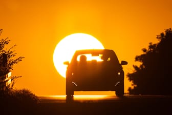 Auto entfernt sich vom Sonnenaufgang (Symbolfoto): Die neue Woche wird heiß in Sachsen – und überrascht immer wieder mit Gewittern.