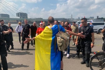 In Köln haben am Rhein zeitgleich der "Ukraine-Tag" und eine umstrittene prorussische Demo stattgefunden: Dieser Mann mischte sich mit ukrainischer Flagge unter die Russen.