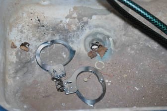 Handschellen liegen in einem dreckigen Waschbecken (Symbolfoto): Die Jugendbande steht ebenfalls im Verdacht, im großen Stil mit Drogen gehandelt zu haben.