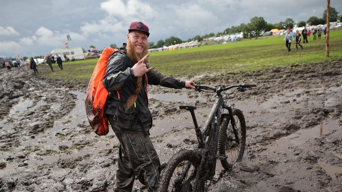 Lukas Litwin aus Bochum ist mit seinem E-Mountainbike auf dem schlammigen Festivalgelände des Wacken-Open-Air unterwegs.
