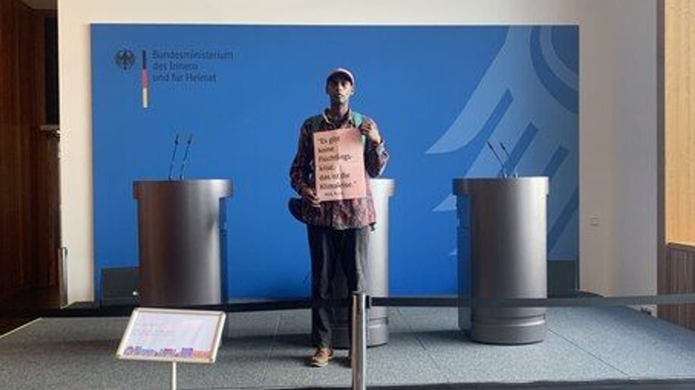 Ein Aktivist bei der Protestaktion am Sonntag im Innenministerium. Auf dem Schild stand: "Es gibt keine Flüchtlingskrise, das ist die Klimakrise."