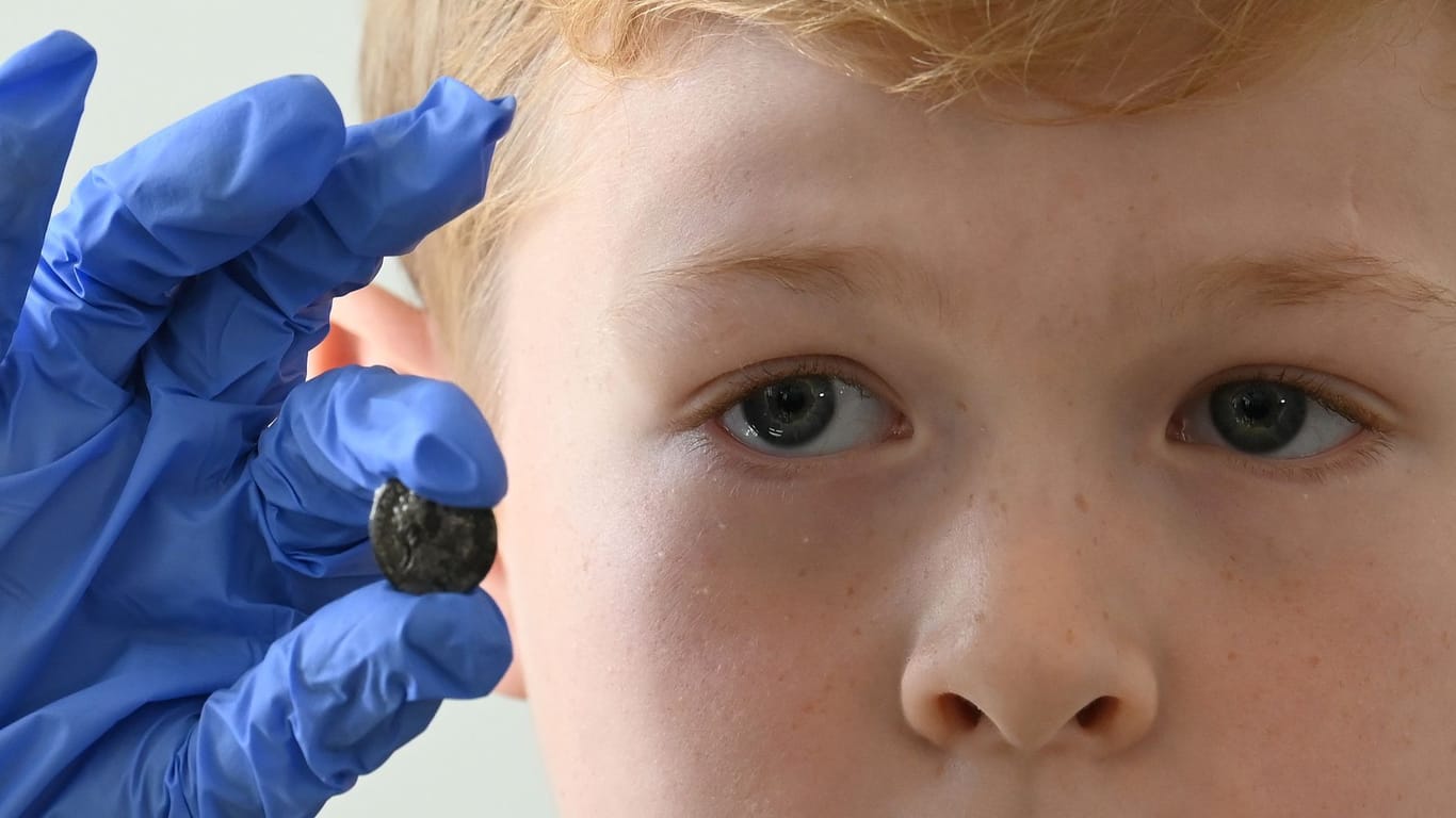 Der achtjährige Bjarne hält die 1.800 Jahre alte Münze, die er 2022 beim Spielen gefunden hatte.