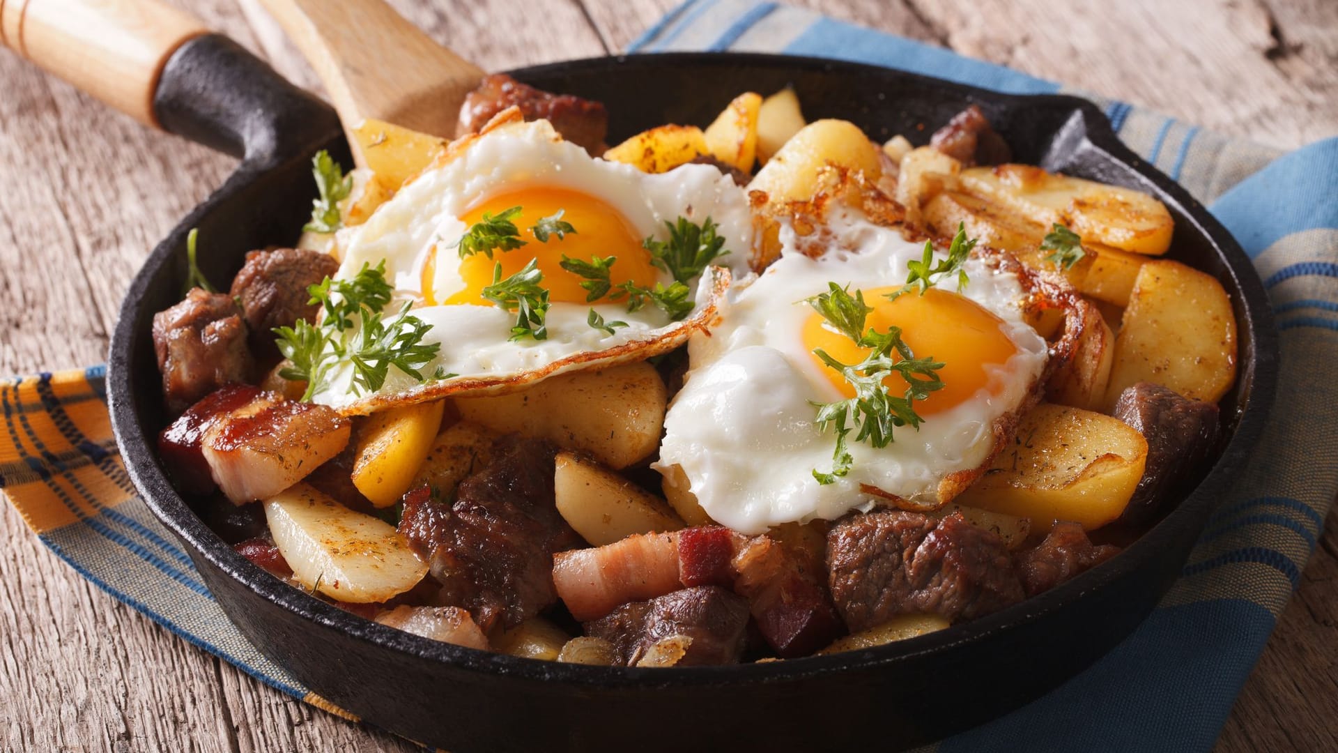 Klassische Bratkartoffeln mit Spiegeleiern und Speck.