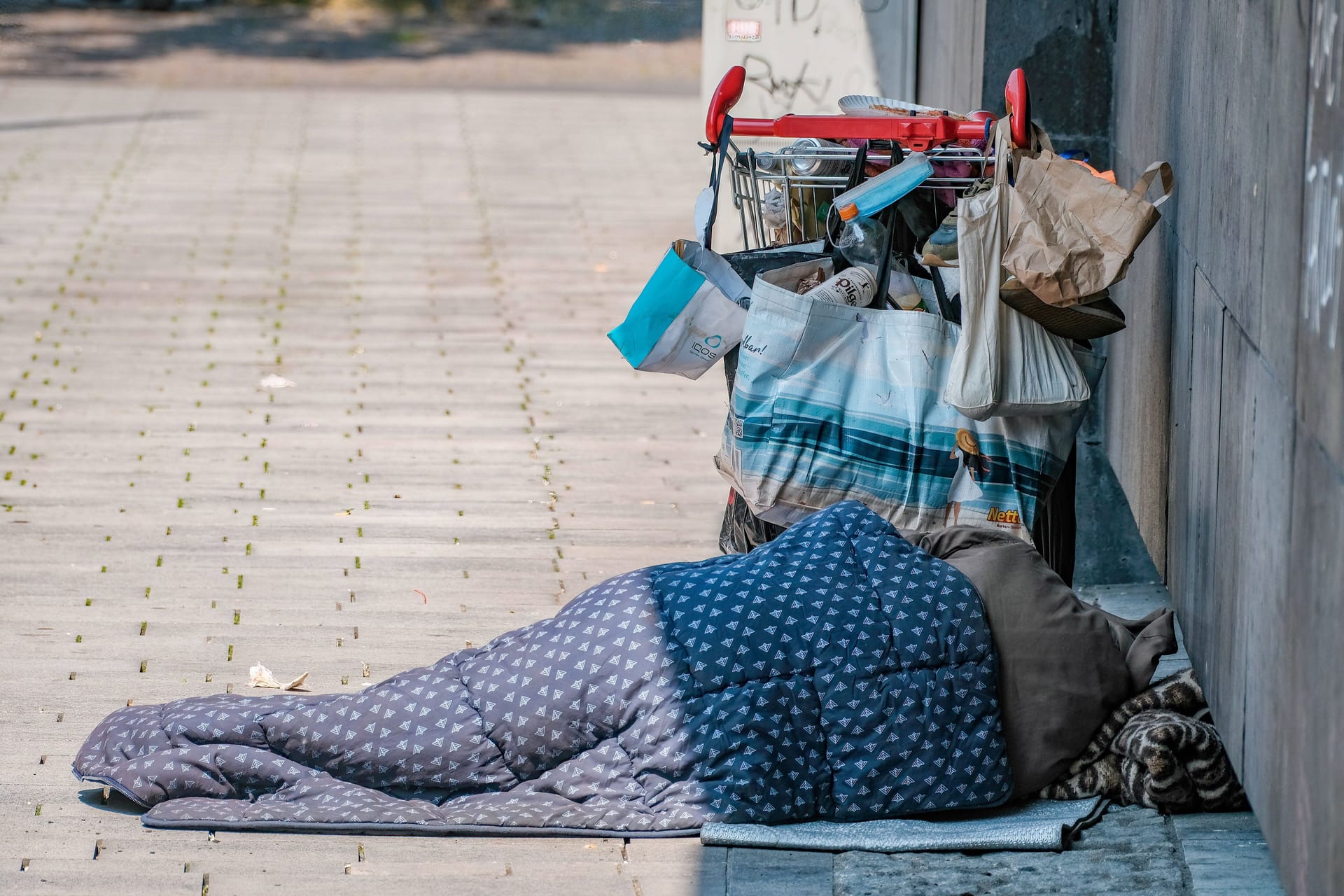 Auf den Straßen von Düsseldorf: Ein Obdachloser schläft neben seinem Einkaufswagen.