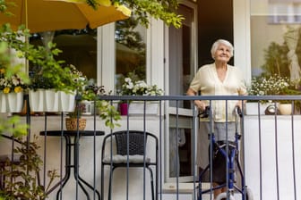 Rentnerin auf ihrem Balkon (Symbolbild): Im Alter kann schon mal ein Umzug anstehen. Hat der Verkauf der Wohnung dann Folgen für die Witwenrente?