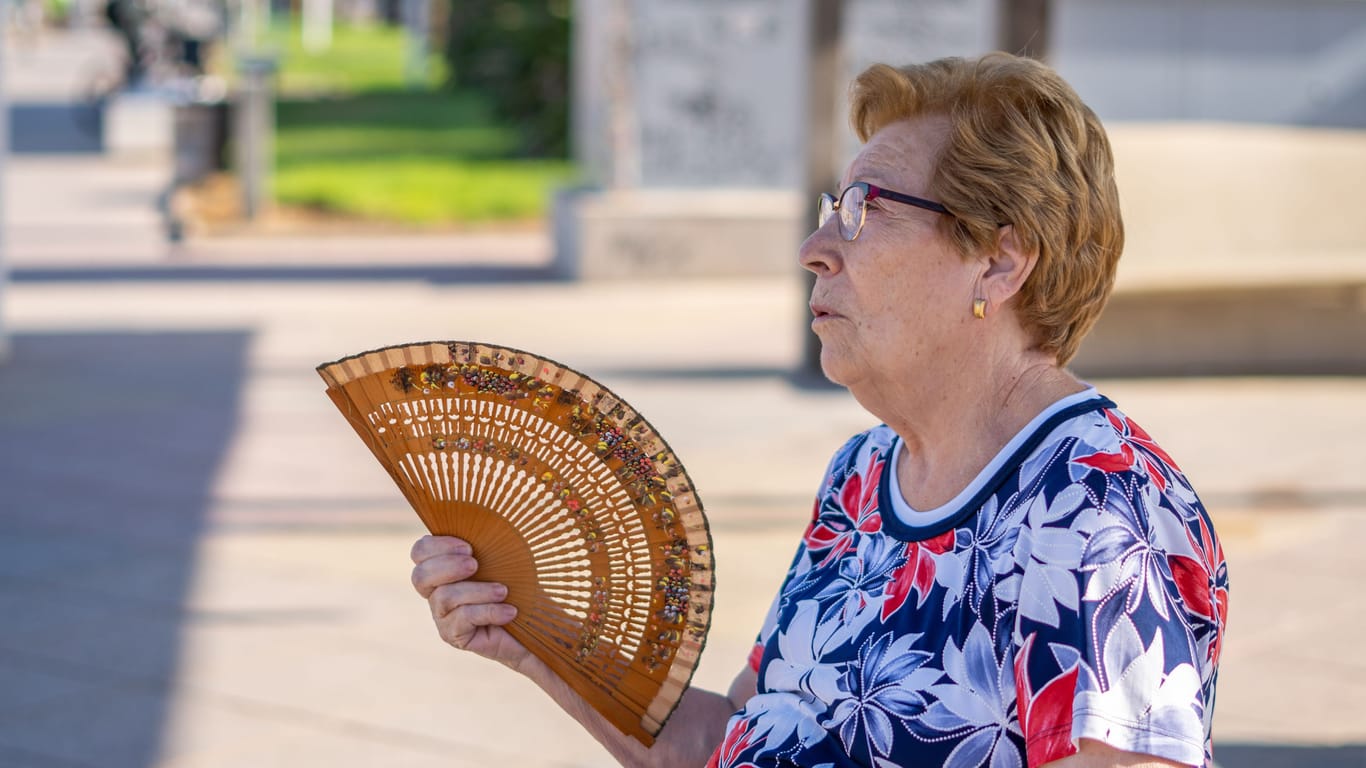 Eine ältere Frau fächert sich im Schatten Luft zu (Symbolbild): Auch in Deutschland kletterten die Temperaturen teils Richtung 40 Grad.
