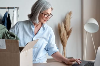 Frau mit online bestellter Kleidung (Symbolbild): Der Versandhändler Madeleine ist insolvent, das Geschäft läuft vorerst weiter.