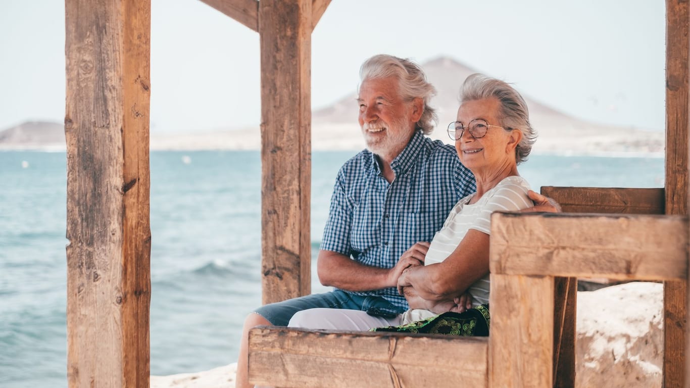 Rentnerpaar blickt hinaus aufs Meer: Wer im Alter noch einmal Lust auf ein Abenteuer hat, kann über einen Umzug ins Ausland nachdenken.