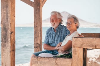 Rentnerpaar blickt hinaus aufs Meer: Wer im Alter noch einmal Lust auf ein Abenteuer hat, kann über einen Umzug ins Ausland nachdenken.