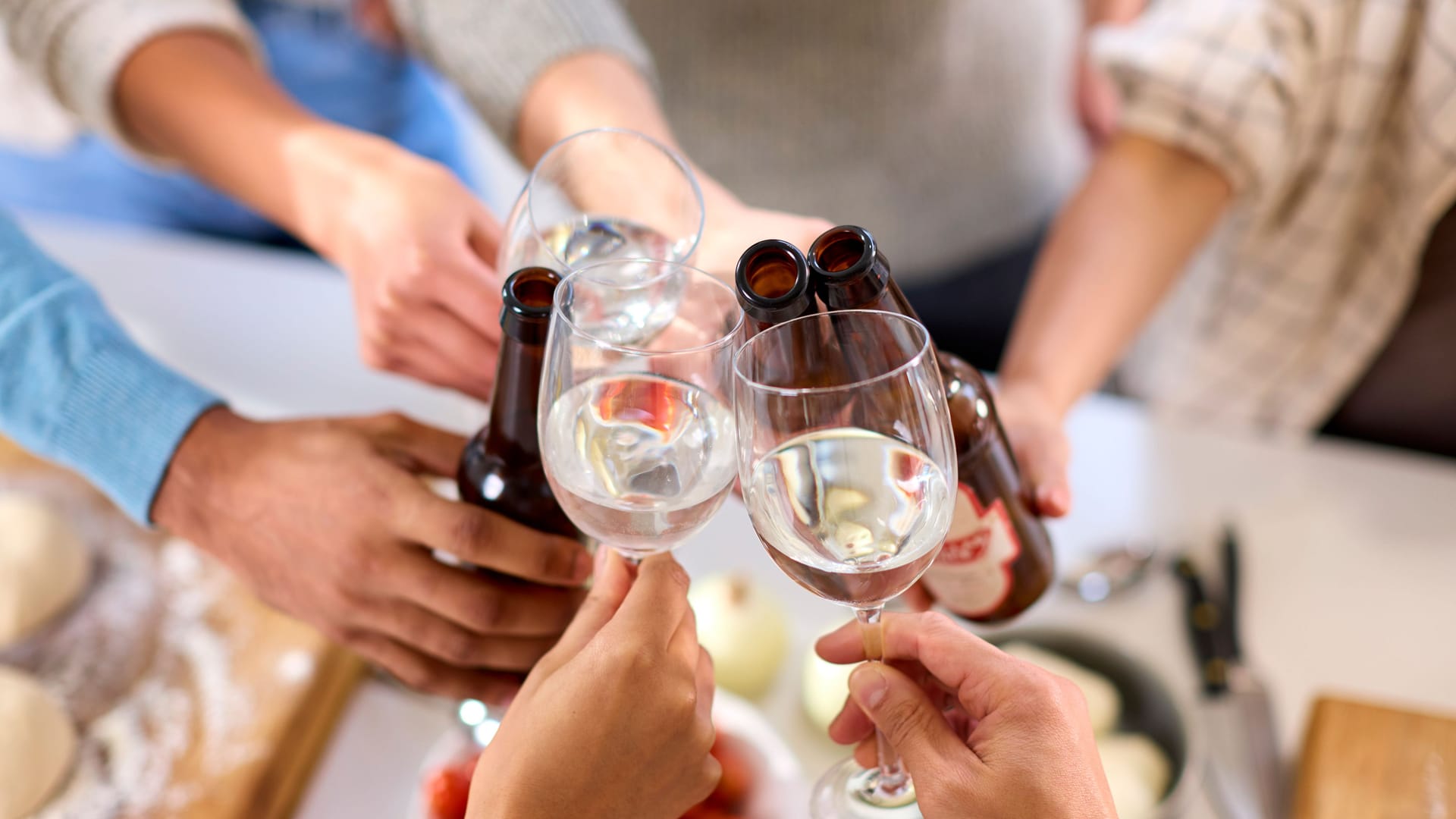 Mehrere Personen stoßen mit Bier und Wein an.