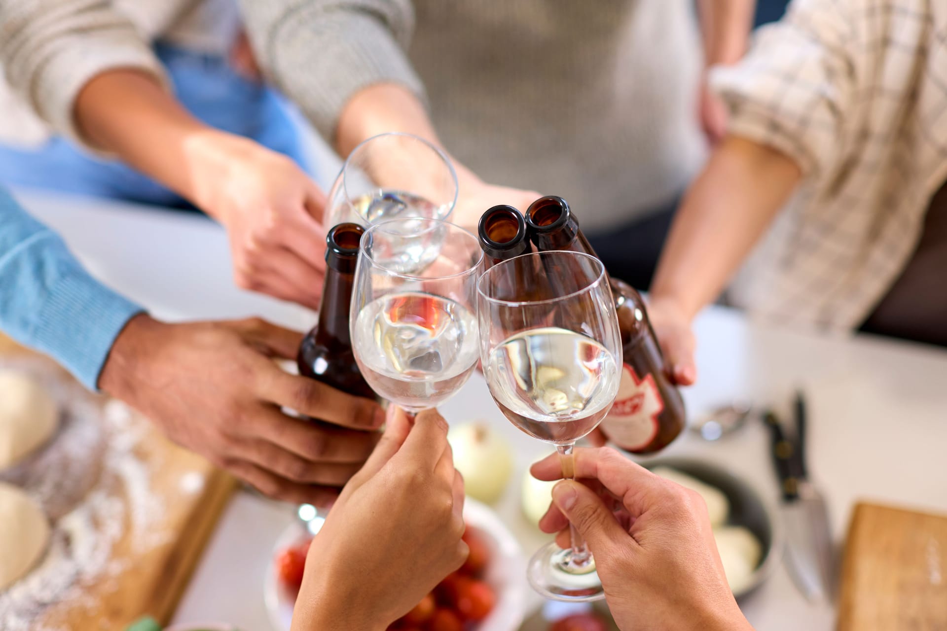 Mehrere Personen stoßen mit Bier und Wein an.