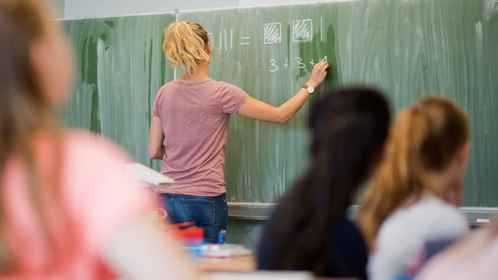 Eine Lehrerin schreibt an eine Schultafel (Symbolfoto): Bei Teilzeitkräften könne beispielsweise eine Aufstockung auf Vollzeit erfolgen, so die Idee. Eine Lehrerin schreibt an eine Schultafel (Symbolfoto): Bei Teilzeitkräften könne beispielsweise eine Aufstockung auf Vollzeit erfolgen, so die Idee.
