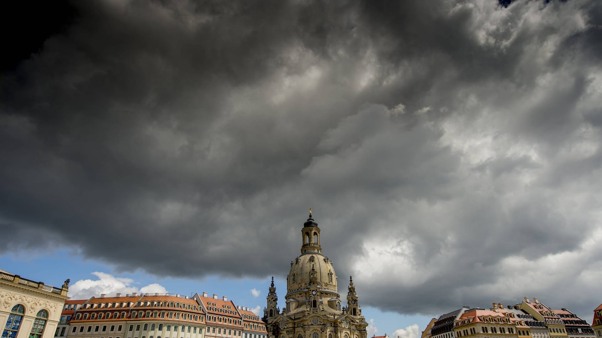 Dunkle Regenwolken ziehen über der Frauenkirche auf: Die Menschen in Sachsen müssen sich auf einen Wetterumschwung einstellen.