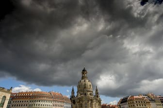 Dunkle Regenwolken ziehen über der Frauenkirche auf: Die Menschen in Sachsen müssen sich auf einen Wetterumschwung einstellen.