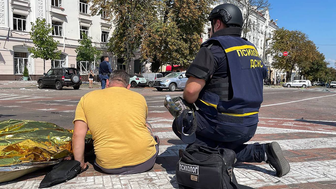 Ein ukrainischer Helfer betreut ein Opfer des russischen Raketenangriffs auf einem zentralen Platz in Tschernihiw.