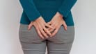 Frau mit Gesäßschmerzen: Machen sich am Steißbein Schmerzen bemerkbar, vermuten manche Betroffene bösartige Erkrankungen wie Darmkrebs als Ursache.