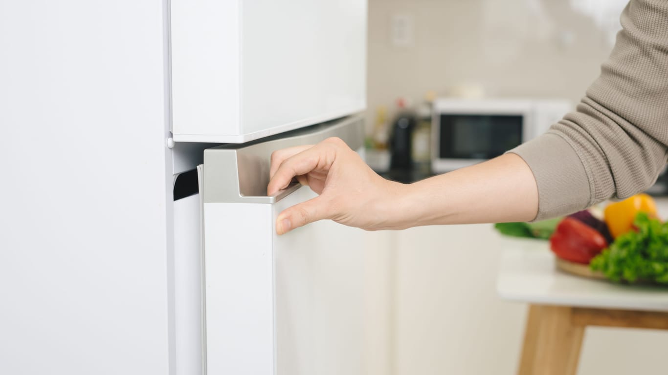 Eine Person öffnet das Gefrierfach eines Kühlschranks