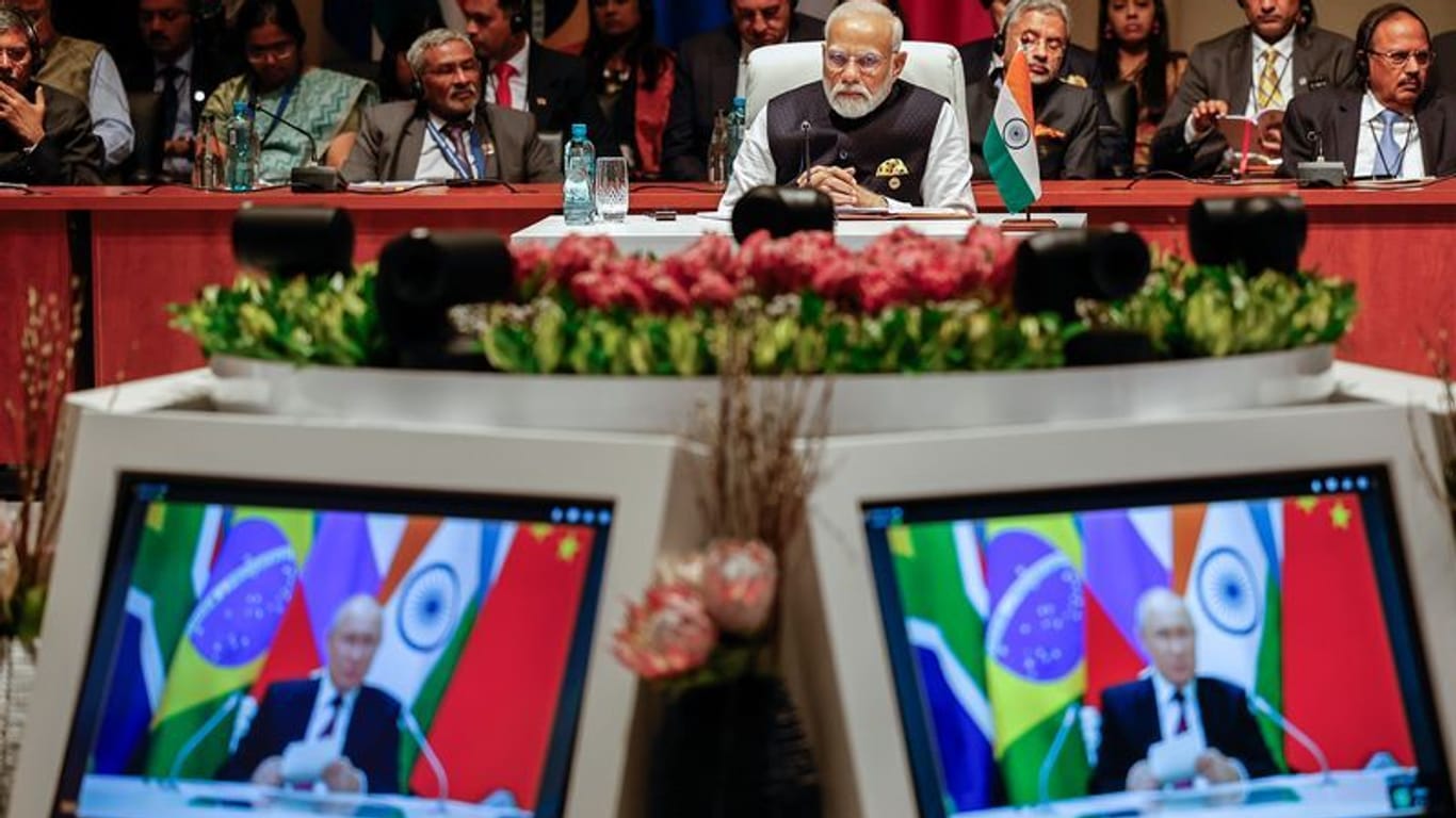 Indiens Premierminister Narendra Modi (M) schaut der Plenarsitzung auf dem Brics-Gipfel 2023 zu, während Kremlchef Wladimir Putin per Videoübertragung spricht.