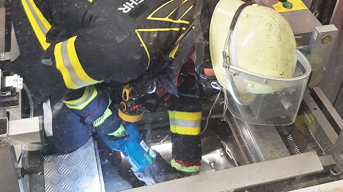 Ein Feuerwehrmann setzt eine Säge an, um ein Loch in das Dach des Aufzugs zu schneiden.