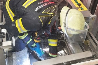 Ein Feuerwehrmann setzt eine Säge an, um ein Loch in das Dach des Aufzugs zu schneiden.