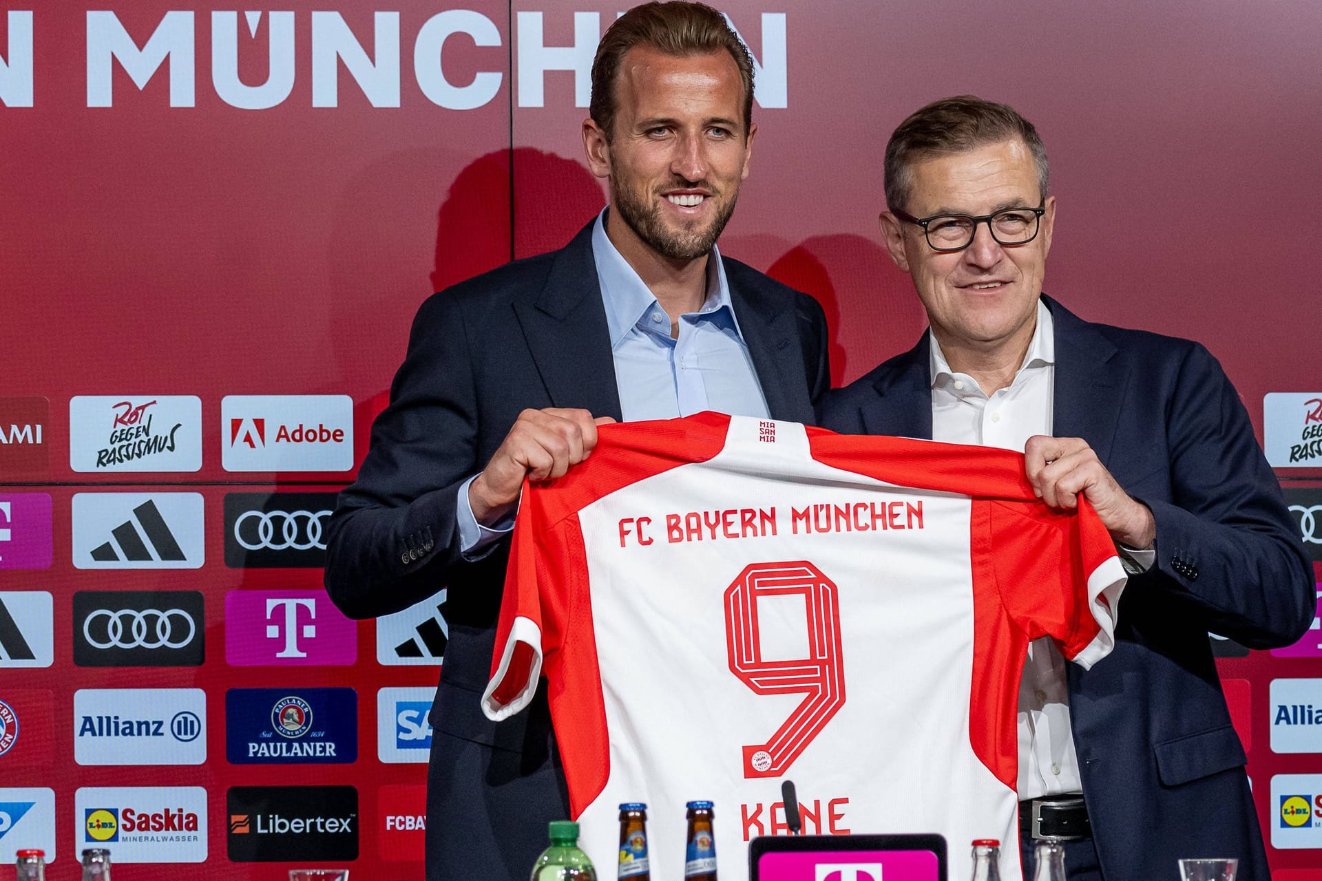 Harry Kane (l.) und Jan-Christian Dreesen mit dem Trikot des Stürmers: Der Neuzugang spült schon ordentlich Geld in die Kassen des FC Bayern.