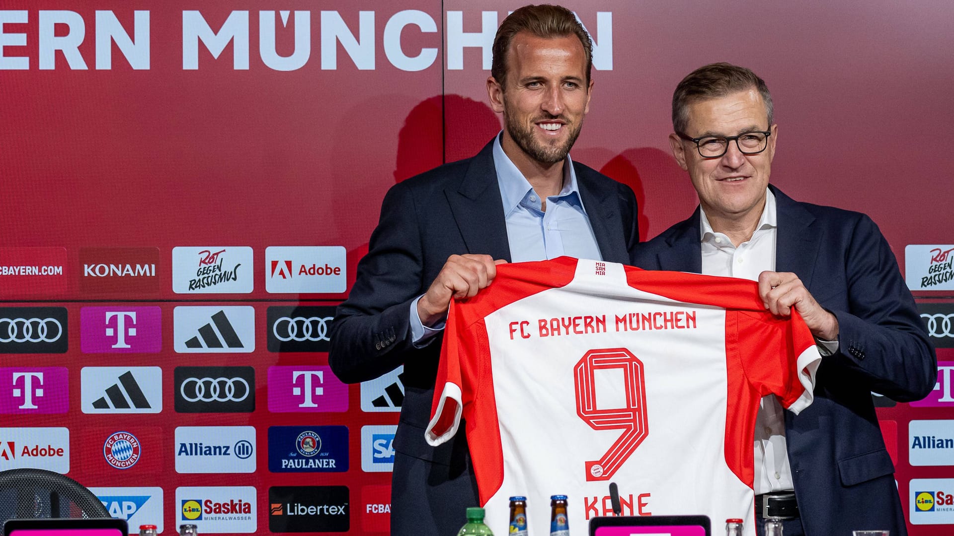 Harry Kane (l.) und Jan-Christian Dreesen mit dem Trikot des Stürmers: Der Neuzugang spült schon ordentlich Geld in die Kassen des FC Bayern.