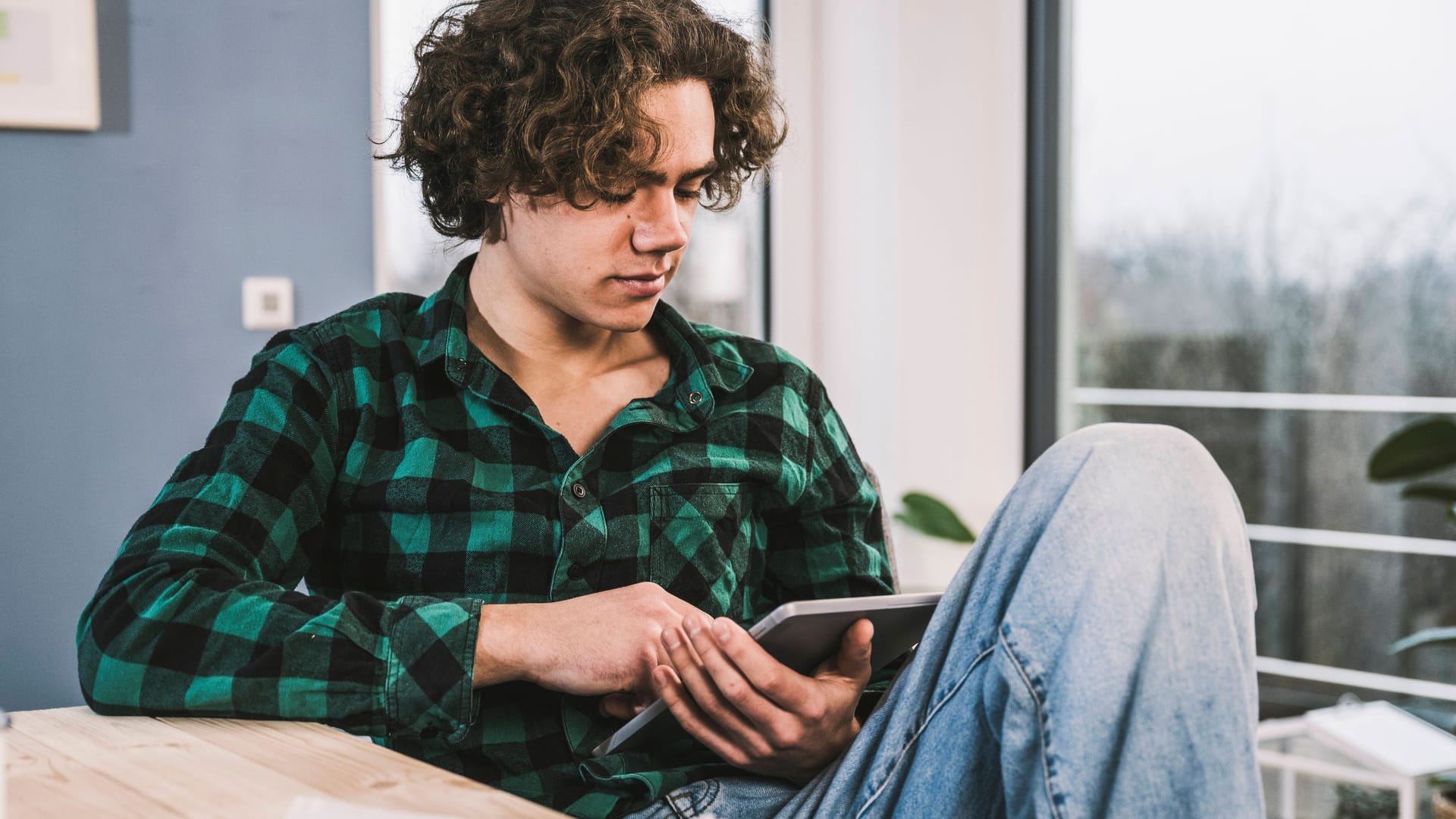 Junger Mann am Tablet (Symbolbild): Junge Menschen sind eher unzufrieden, als ältere Menschen in Deutschland.