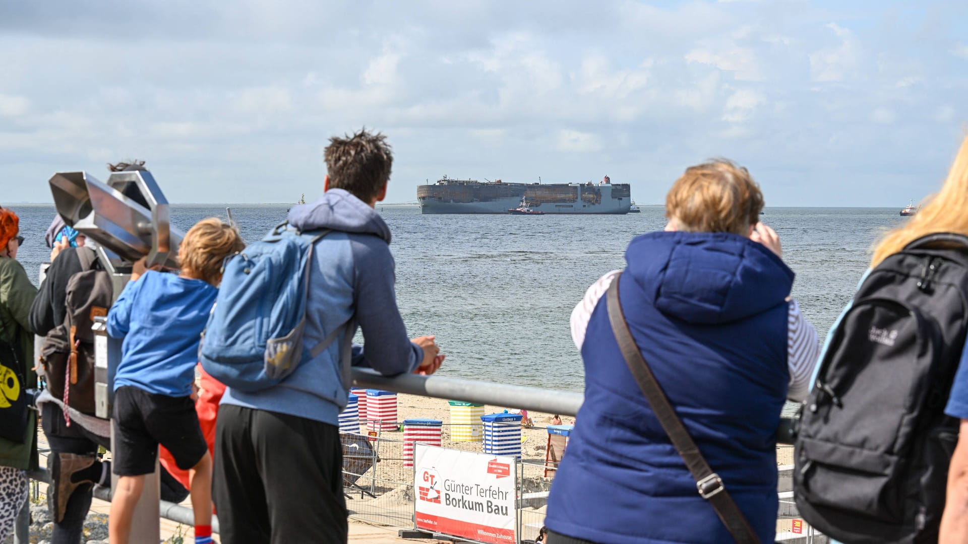 Menschen beobachten, wie der verbrannte Frachter an Borkum vorbeigezogen wird. Menschen beobachten, wie der verbrannte Frachter an Borkum vorbeigezogen wird.