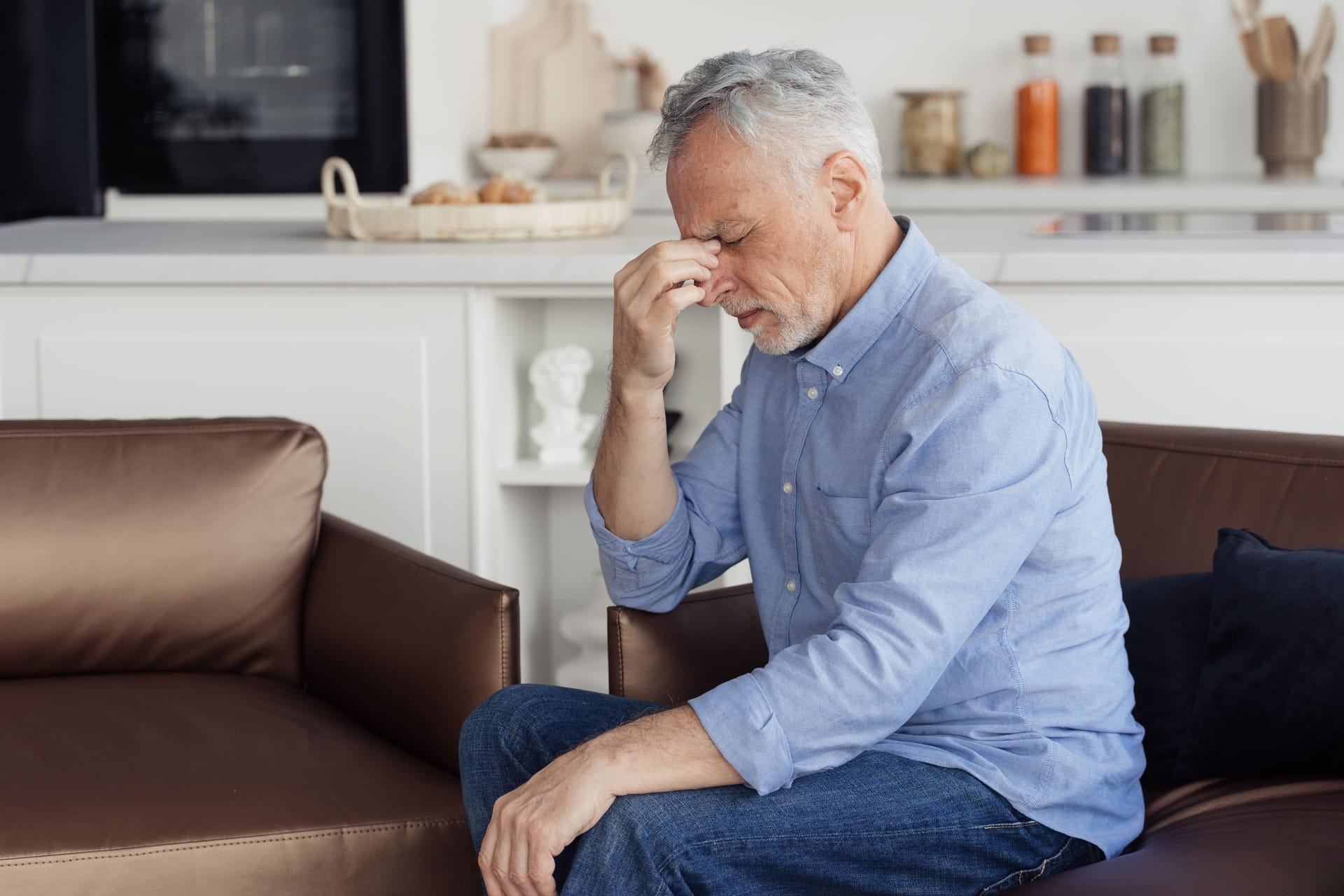 Ein Mann sitzt auf dem Sofa und leidet an Kreislaufproblemen